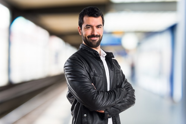 Man met lederen jas met zijn armen gekruist op onfocused achtergrond