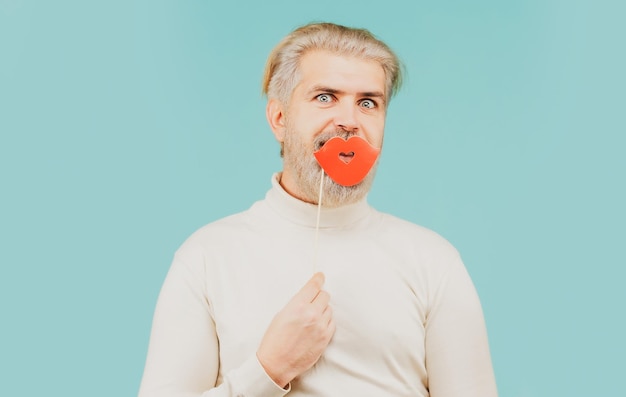 Man met lippen van fotohokje Man met feestlippen op stok Bebaarde hipster met fotohokje Man stuurt luchtkus met rode lippen