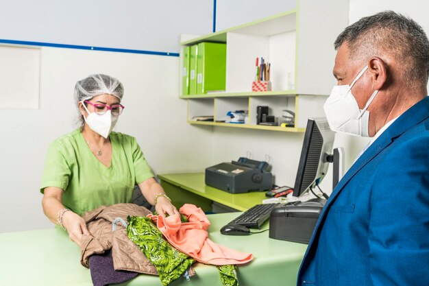 Man met masker laat de was achter bij de balie van een wasserette