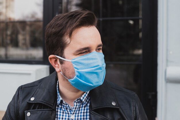 Man met masker op een achtergrond van gesloten café, coronavirus, ziekte, infectie, quarantaine, medisch masker