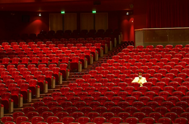 Man met masker zit op stoelen in het theater