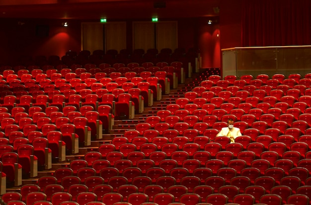 Foto man met masker zit op stoelen in het theater