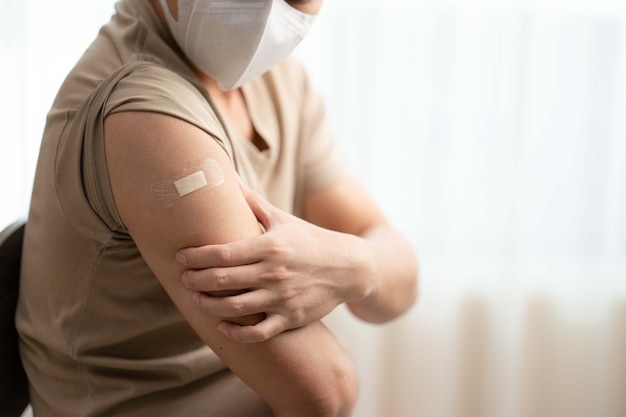 Man met maskerarm met verband dat zijn arm laat zien na het ontvangen van vaccin