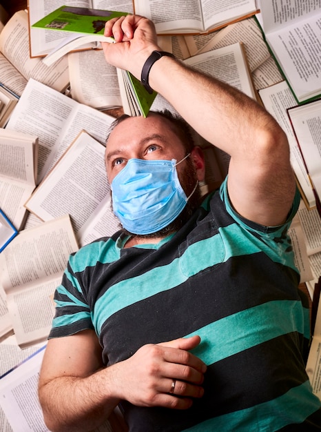 Man met medisch masker met veel papieren boeken