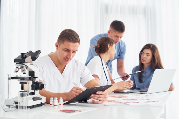 Man met microscoop Groep jonge artsen werkt samen in het moderne kantoor