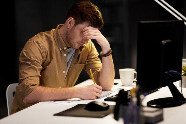 Man met notepad die laat's nachts in het kantoor werkt