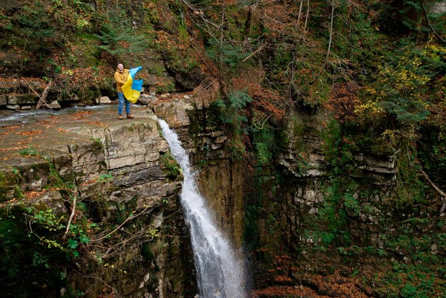 Man met oekraïense vlag op de top van de waterval