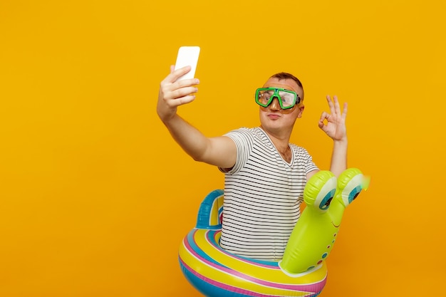 Man met onderwatermasker, gestreept shirt, baantjes zwemmen in de telefoon kijken, een selfie nemen