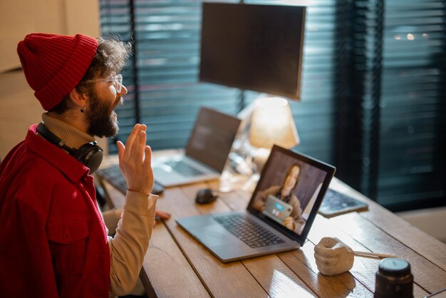 Man met online ontmoeting met vrouwelijke collega terwijl hij thuis werkt