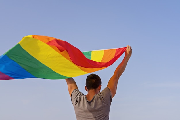 Man met opgeheven handen zwaaien LGBT regenboogvlag