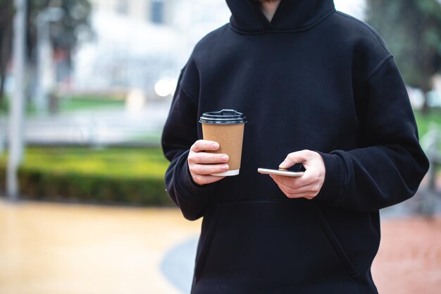 Man met papieren beker en smartphone buitenshuis