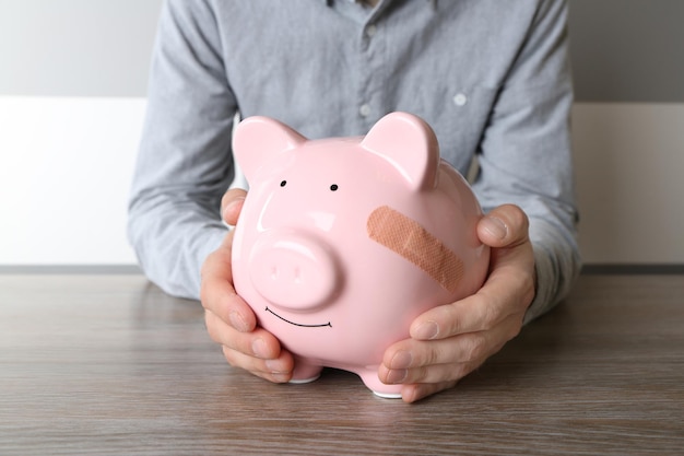 Man met Piggy Bank met zelfklevend verband op witte achtergrond