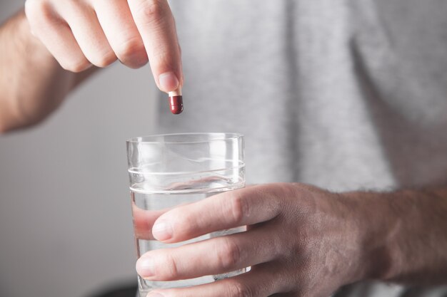 Man met pil en een glas water.