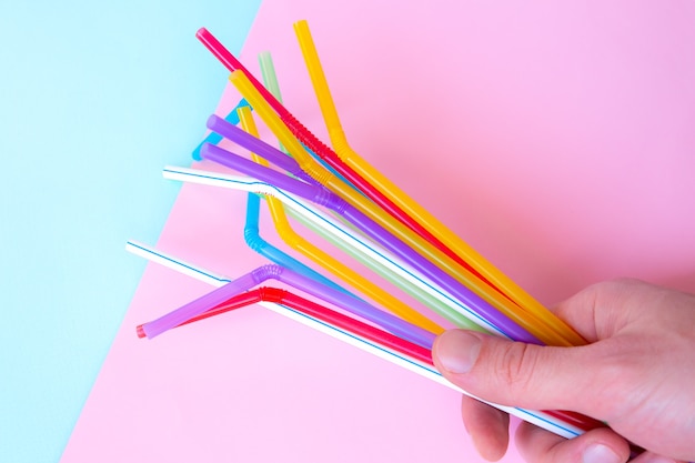 Man met plastic rietjes voor cocktails. pastelroze en blauwe kleuren. zomerse sferen. hipsterfeestje met drankjes.