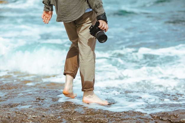 Man met professional kwam in de hand wandelen langs het rotsachtige strand van de zee