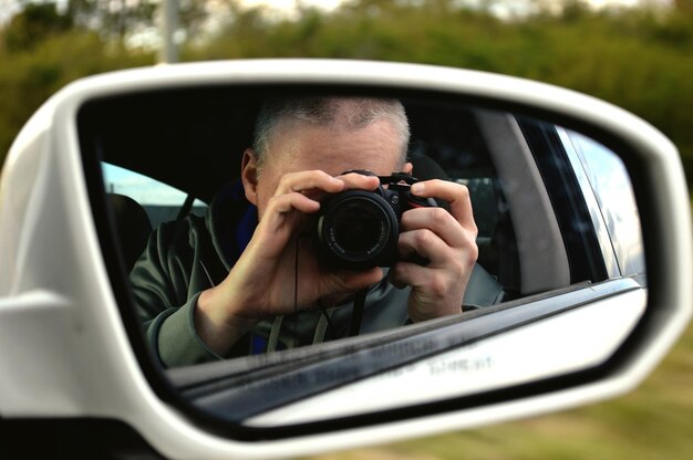 Foto man met reflectie in de zijkantspiegel van een auto