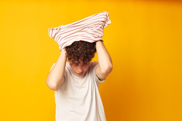 Man met rood krullend haar die een gestreept t-shirt aantrekt en zich ongewijzigd op een geïsoleerde achtergrond stelt