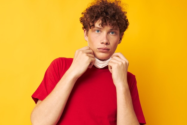 Man met rood krullend haar in een rood t-shirt medische maskerbescherming Levensstijl ongewijzigd