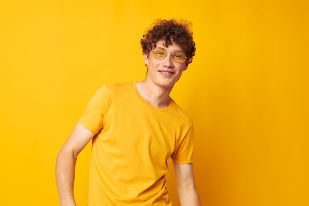 Man met rood krullend haar jeugdstijl bril studio vrijetijdskleding gele achtergrond ongewijzigd