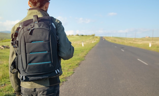 Man met rugzak die op de weg staat