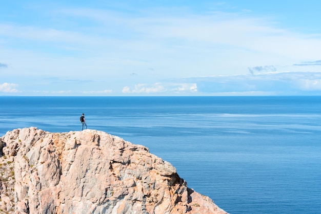 Man met rugzak staande op een rots aan het einde van de aarde kijkend op het helderblauwe meer Wandel- of reisconcept Het verkennen van het buitenleven Schoonheid van de natuur