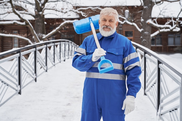 Man met schop op schouder in de winter