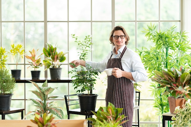 man met schort in kas koffie drinken