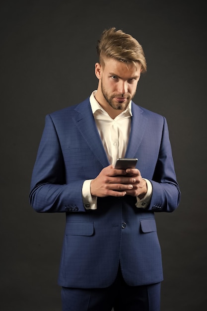 Man met serieus gezicht in formele outfit met mobiele telefoon