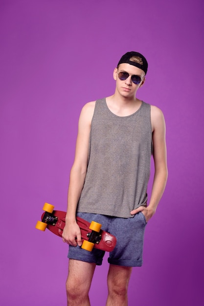 Man met skate board in de hand op paarse achtergrond, penny little board