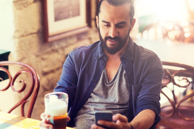 man met smartphone bier drinken in bar of pub