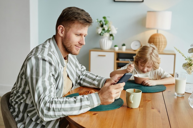 Man met smartphone bij het ontbijt