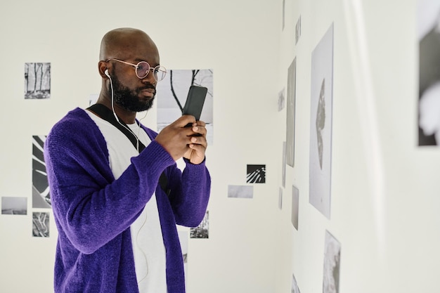 Man met smartphone bij kunstgalerie