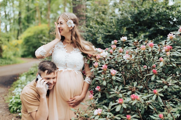 Foto man met smartphone praten met baby op buik van gelukkige zwangere vrouw