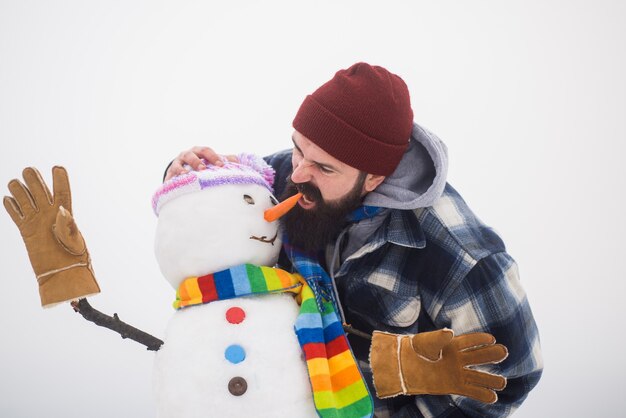 Man met sneeuwpop wintertijd wintervakantie vrije tijd man bijten sneeuwpoppen wortel neus grappig winter