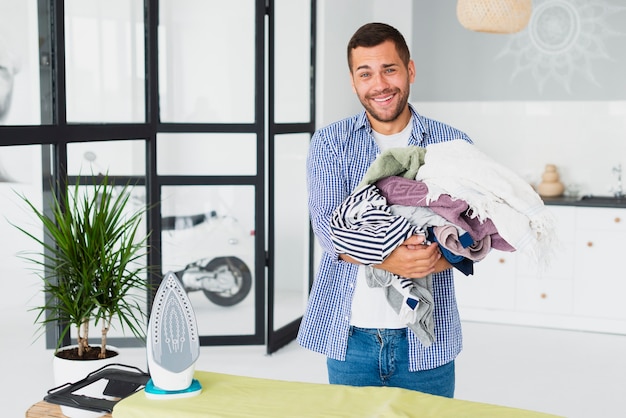 Man met stapel te strijken kleding