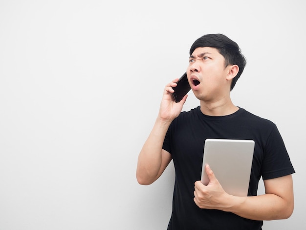 Man met tablet met mobiele telefoon voelt zich geschokt als hij naar kopieerruimte kijkt