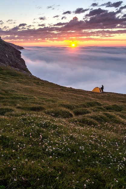 Man met tent bij zonsondergang op de rotsen van het eiland Soroya, Noorwegen