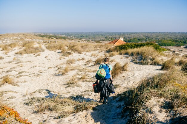 Man met veel tassen in zonnige duinen