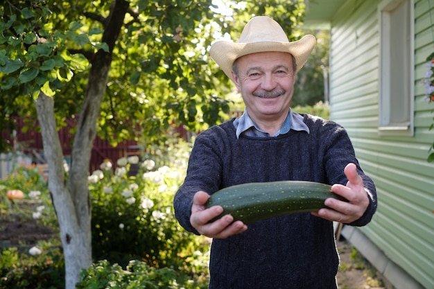 Man met verse groene courgette glimlachend tevreden met zijn herfstoogst