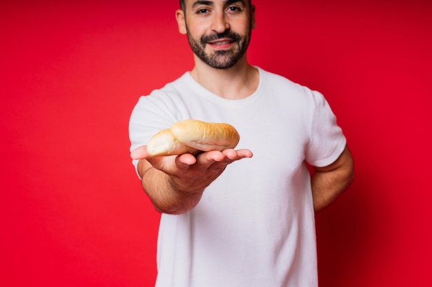 Man met versgebakken brood in de handen geïsoleerd op rode achtergrond studio