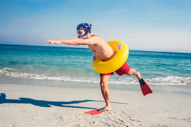 Man met vinnen en rubberen ring op het strand