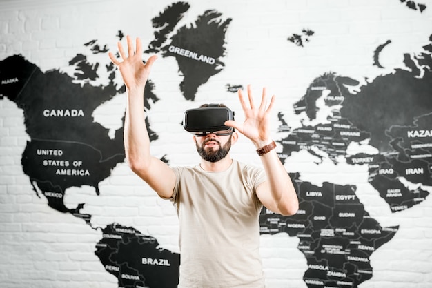 Man met virtual reality-bril die binnen zit met een wereldkaart op de achtergrond