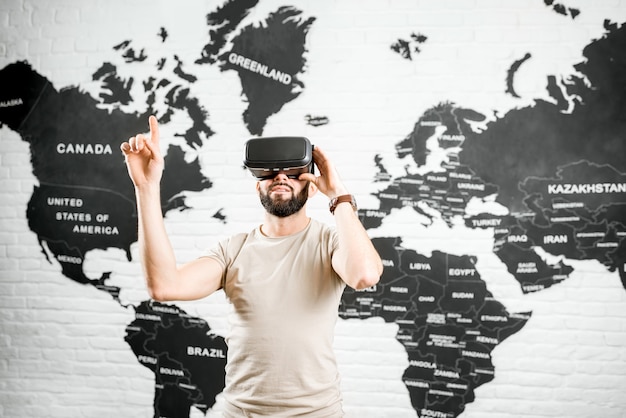 Man met virtual reality-bril die binnen zit met een wereldkaart op de achtergrond