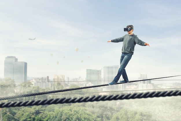 Man met virtual reality-bril en balancerend op touw. Gemengde media