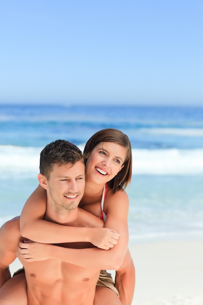 Man met vrouw een piggyback op het strand