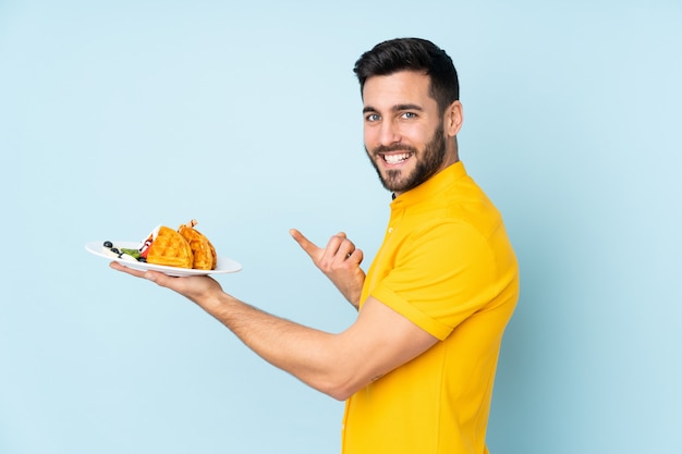 man met wafels op blauw en wijst het