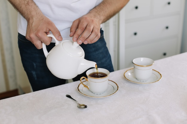 Man met waterkoker die thee maakt