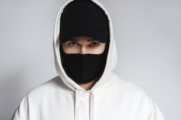 Man met witte hoodie, zwarte baseballpet en stoffen gezichtsmasker