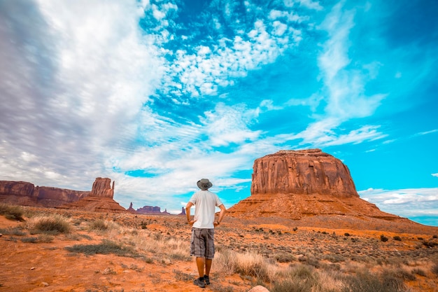 Man met witte t-shirt en groene hoed in het Monument Valley National Park in Three Sisters