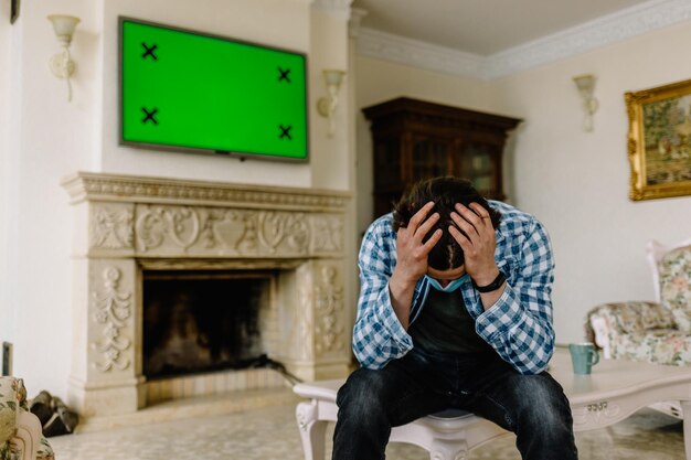 Man met zijn hoofd op een achtergrond van een groen scherm TV